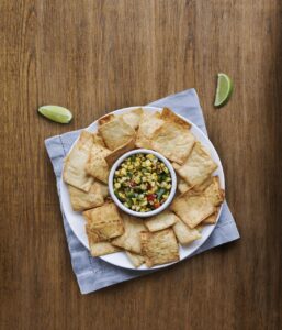 crackers, pita, corn, dip, napkin, bowl, snack, appetizer, lime, crackers, pita, pita, pita, pita, pita, dip