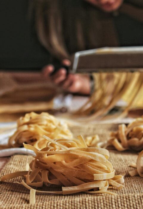 Close-up of handcrafted pasta being made with a pasta machine, showcasing the artisanal process indoors.