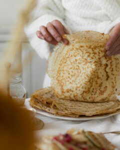 A person prepares homemade pancakes in a cozy kitchen setting, emphasizing rustic charm.