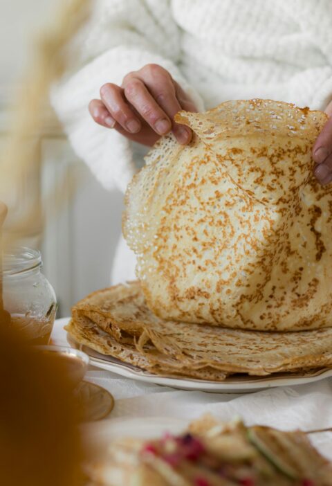 A person prepares homemade pancakes in a cozy kitchen setting, emphasizing rustic charm.