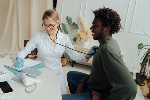 pexels-photo-5215016-5215016 Caucasian female doctor checks black male patient's heart rate with stethoscope in a clinic.