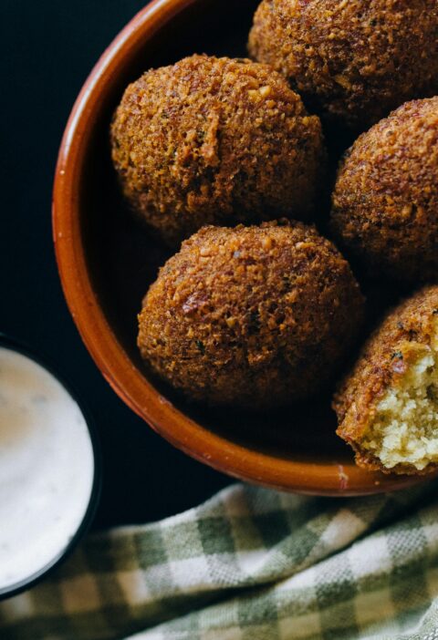 Close-up shot of crispy falafel balls served with creamy tahini sauce in an inviting setting.