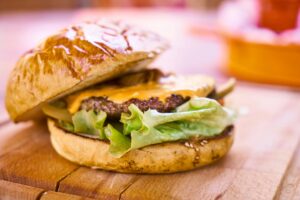Close-up of a delicious cheeseburger with melted cheese and fresh lettuce on a wooden surface.