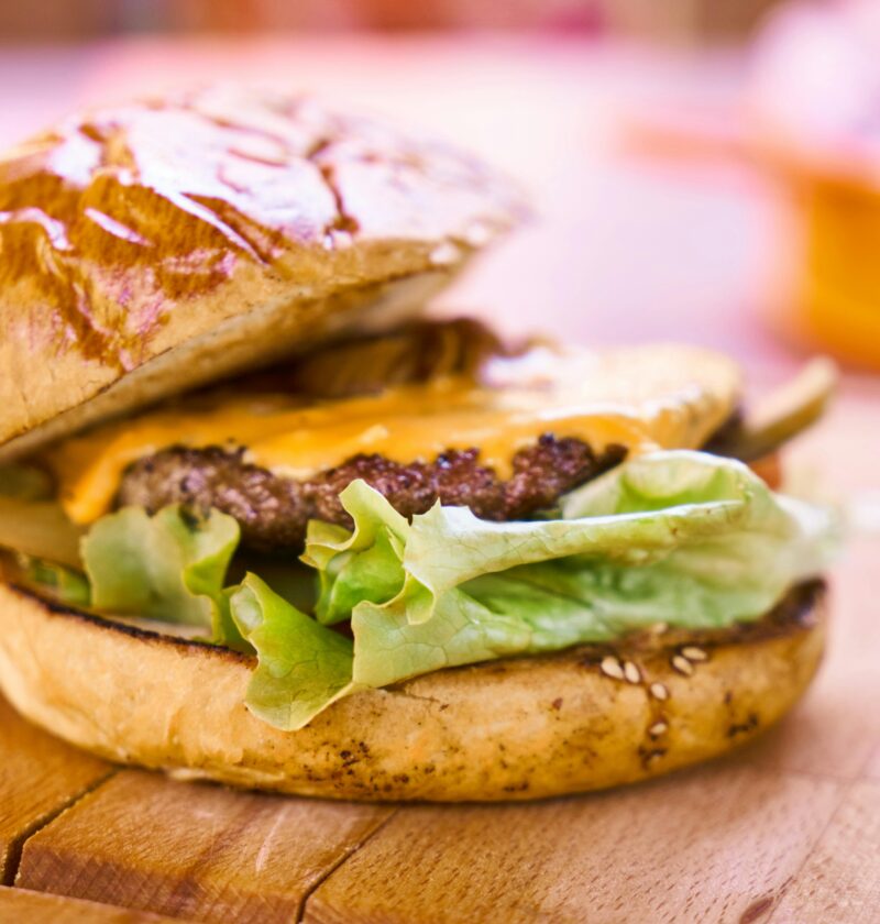 Close-up of a delicious cheeseburger with melted cheese and fresh lettuce on a wooden surface.