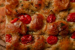 Delicious Italian focaccia with cherry tomatoes and herbs. Perfect for food lovers.