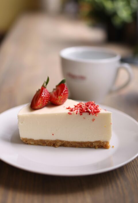 Close-up of a strawberry cheesecake slice on a rustic table, indoors.
