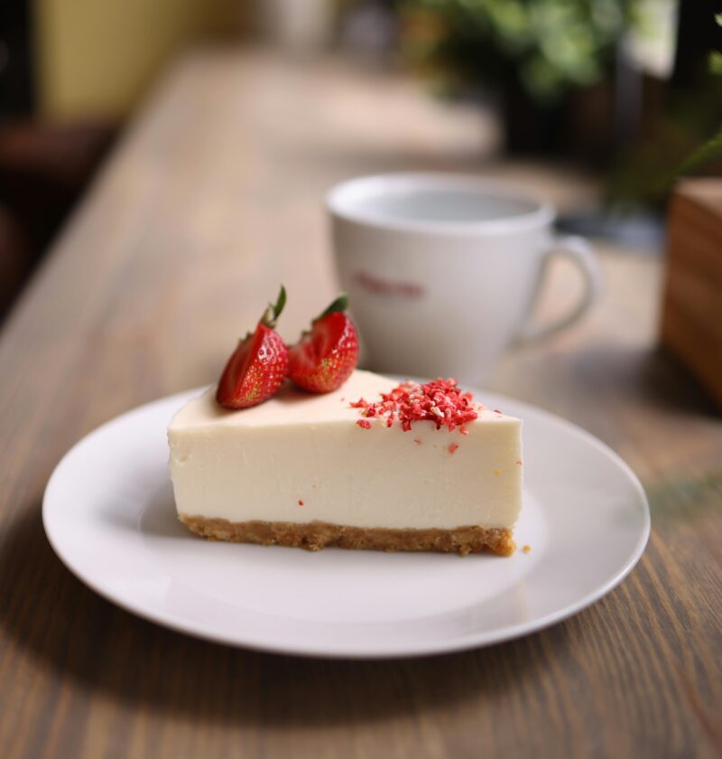 Close-up of a strawberry cheesecake slice on a rustic table, indoors.