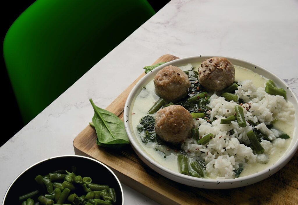 A savory dish of meatballs, rice, and green beans on a decorative plate.