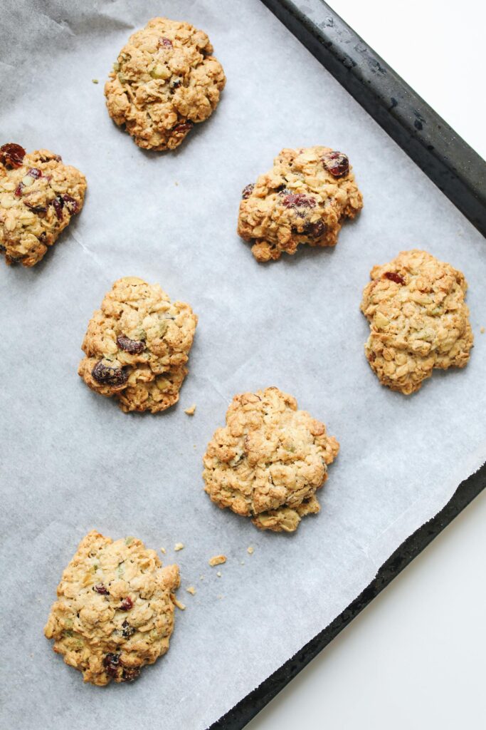Freshly baked homemade oatmeal raisin cookies on a baking tray, perfect for dessert.