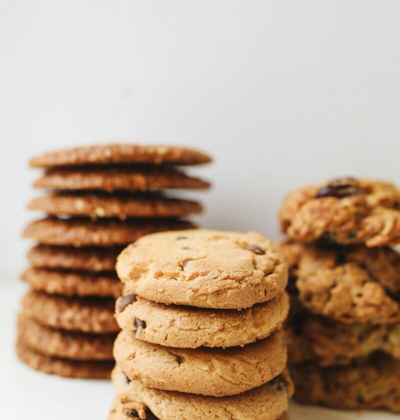 A variety of delicious homemade cookies stacked neatly in piles on a white background.
