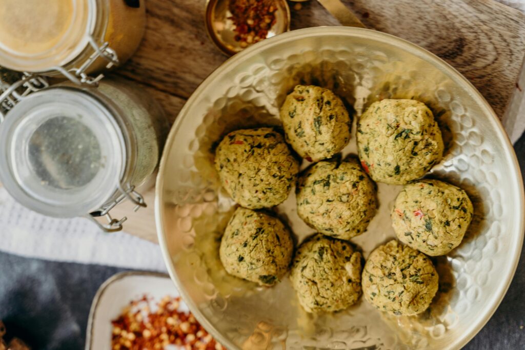 Golden falafel balls served in a bowl with spices on a wooden table.