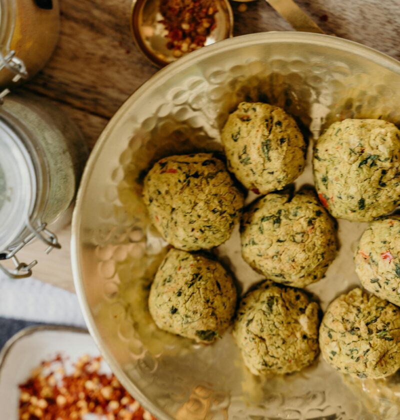 Golden falafel balls served in a bowl with spices on a wooden table.