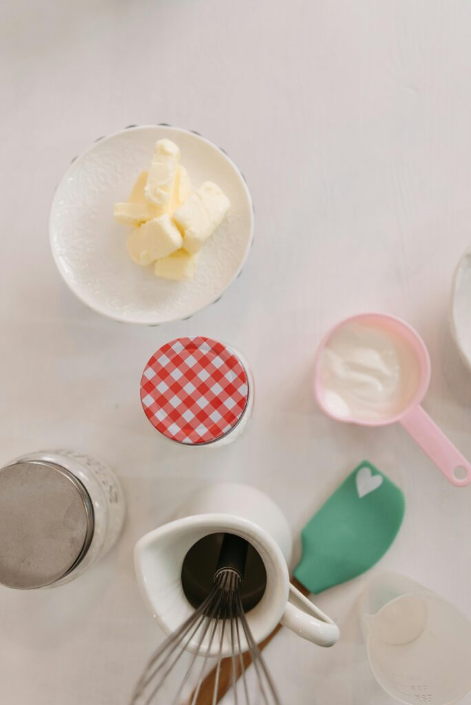 A top-down view of baking ingredients including butter and a whisk on a kitchen table.