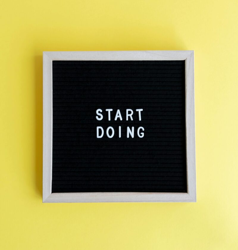 Black message board with 'Start Doing' on a bright yellow background for inspiration.