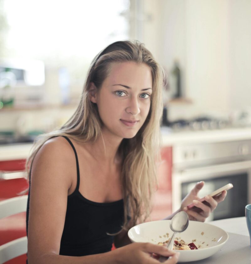 Woman enjoying a healthy breakfast in a modern kitchen, promoting a balanced lifestyle.